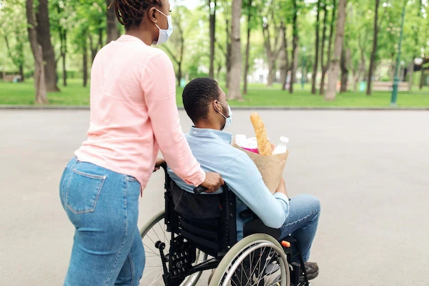 young-black-guy-wheelchair-holding-bag-with-food-returning-home-from-shopping-with-his-wife_116547-19607 (1)