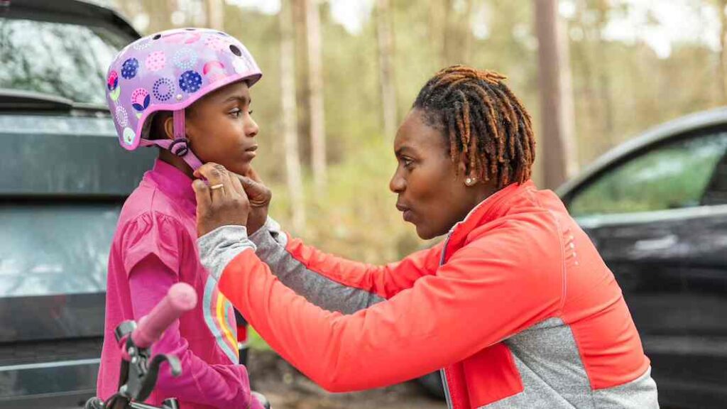 A black mother prepares her daughter for a bicycle ride. Image source: Freepik licensed under CC BY-SA 2.0