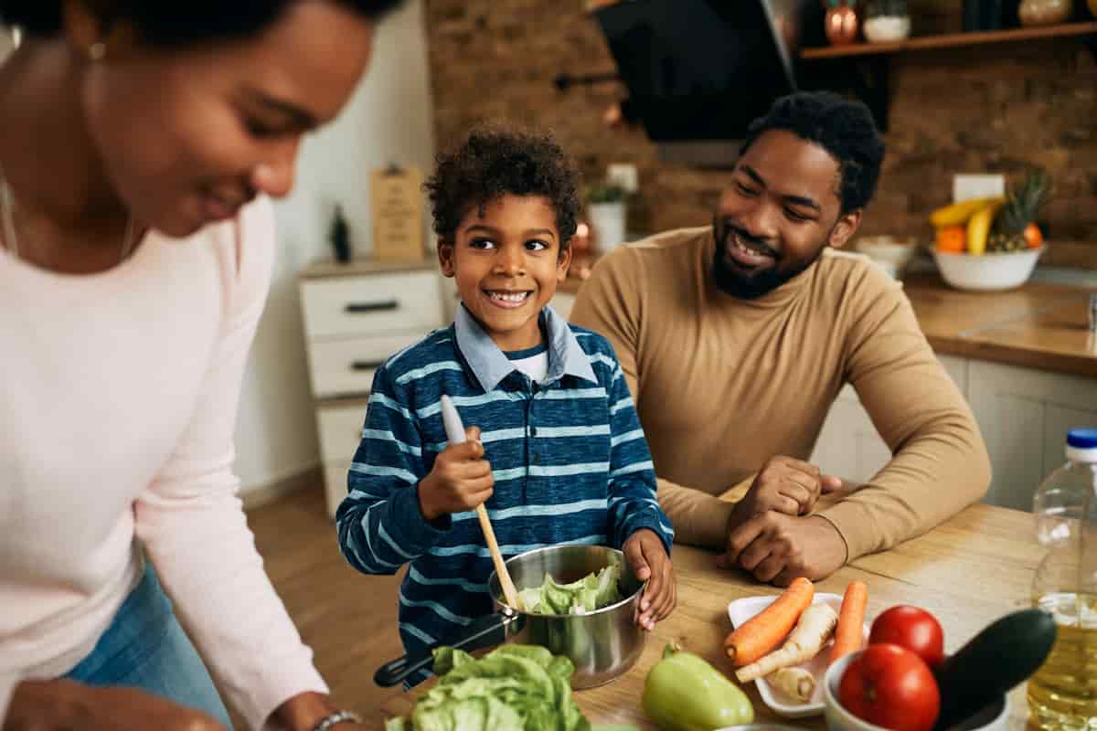spotcovery-happy-black-boy-preparing-healthy-food-with-his-parents-kitchen-healthy-eating