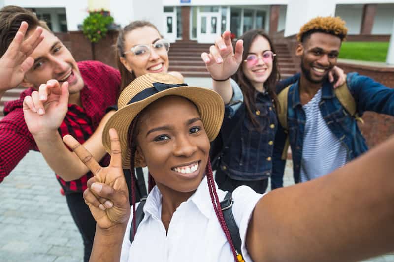 students posing for selfie outside