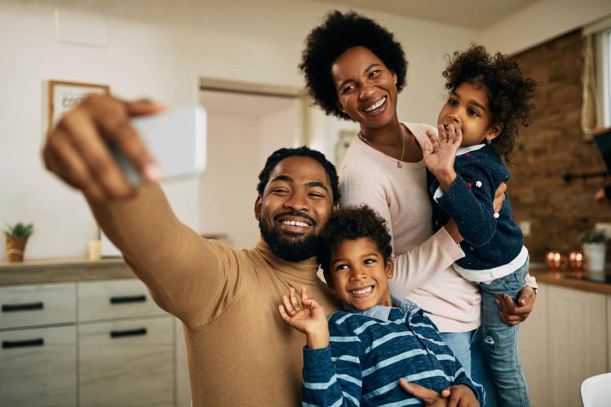 spotcovery-happy-black-parents-with-kids-making-video-call-over-smart-phone-at-home-physical-health-problems-black-community