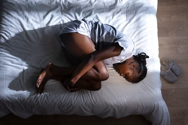 A young girl curled up on a bed. Image source: Freepik licensed under CC BY-SA 2.0
World Day Against Child Labour