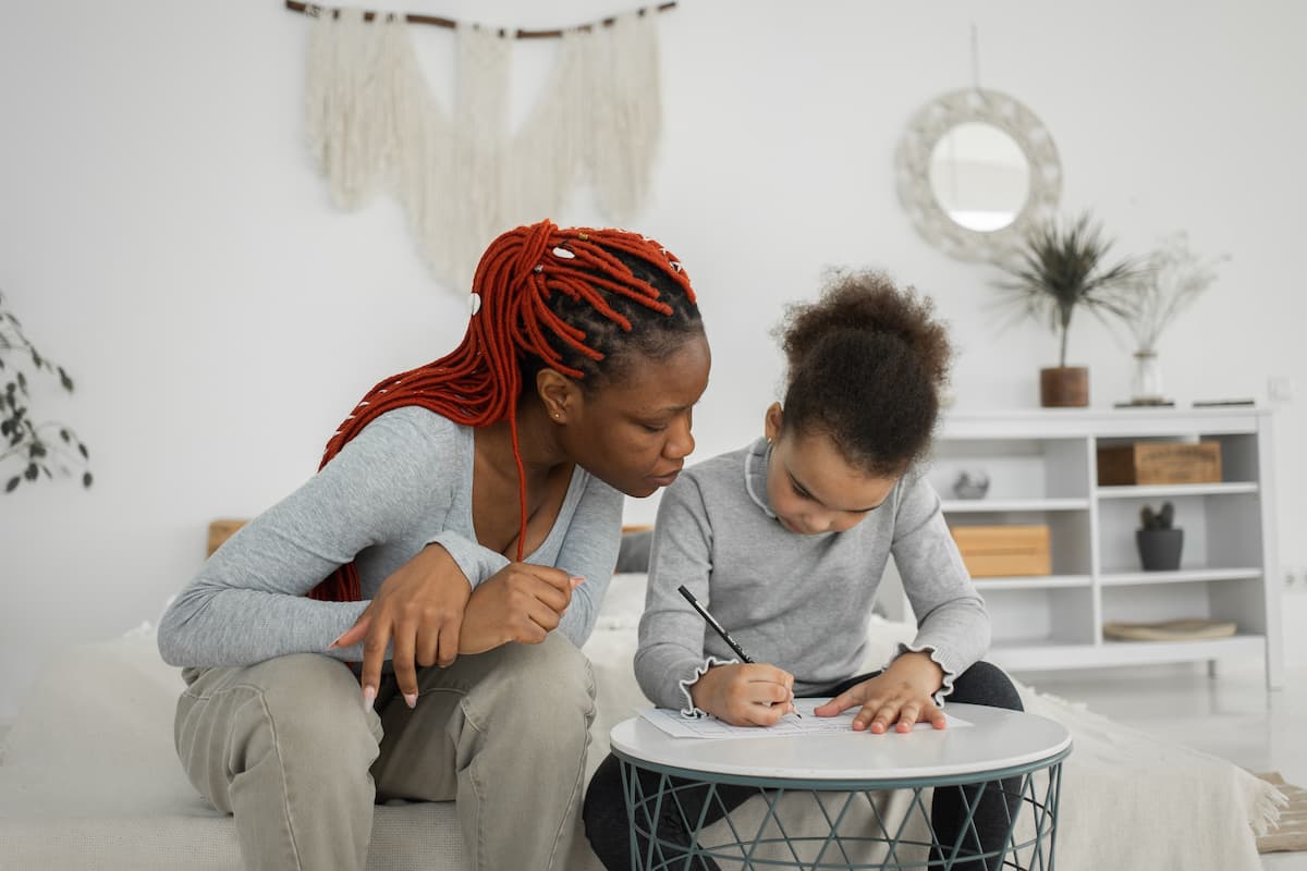 spotcovery-black-woman-and-girl-doing-task-at-table-how-to-save-money-as-a-black stay-at-home-mom