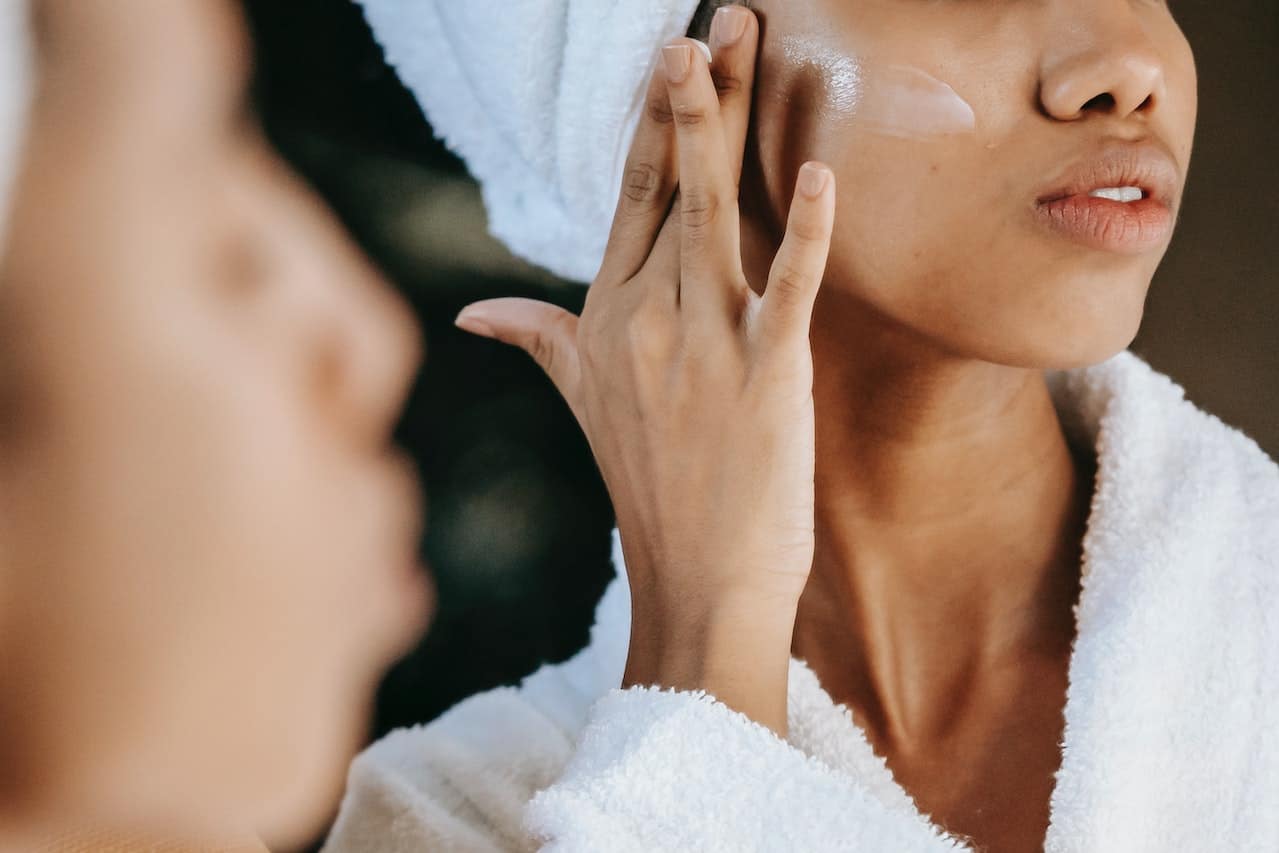 spotcovery-black_woman_applying_moisturizer_that_helps_counter_premature_skin_aging_pexels