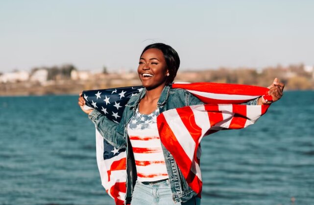 spotcovery-a-smiling-black-woman-holding-American-flag-black-immigrants