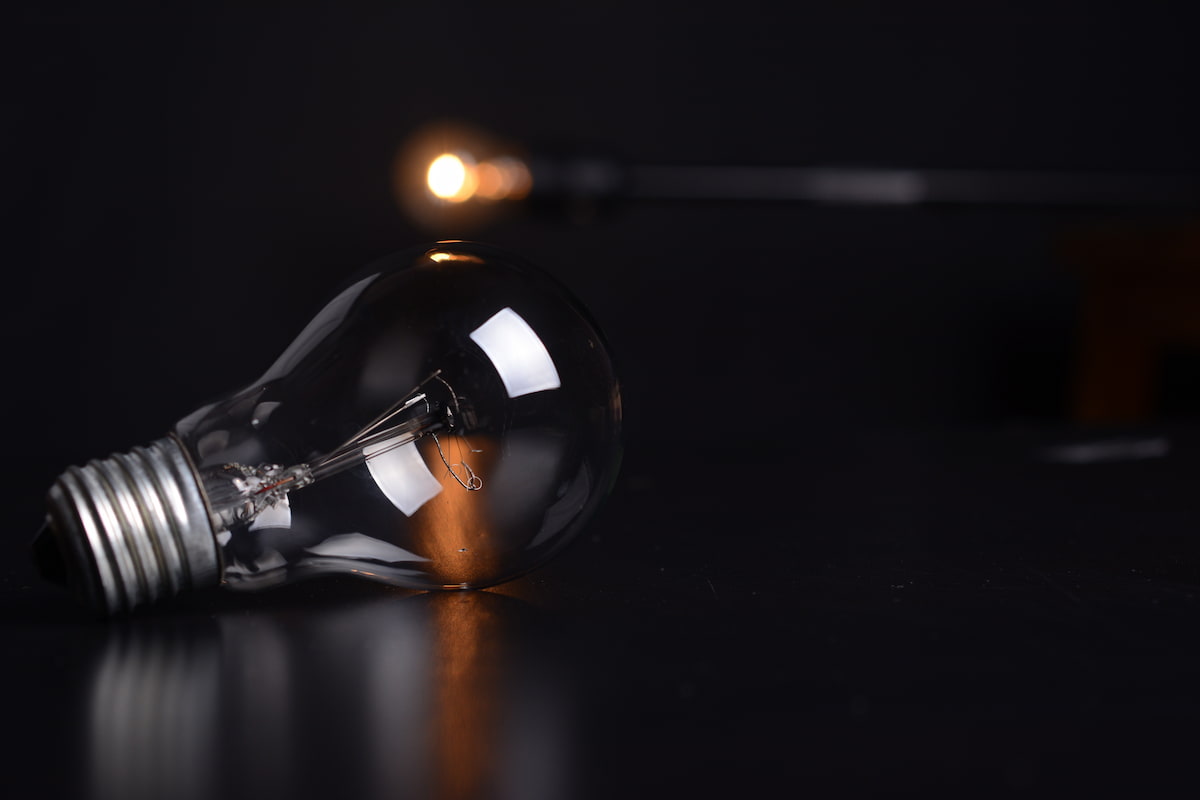spotcovery-clear-filament-bulb-on-black-pad-diving-into-history-the-impact-of-black-technology-background-on-innovation