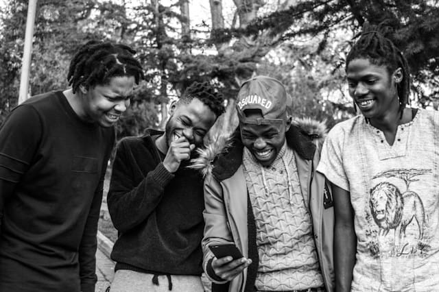 spotcovery-four-men-laughing-while-looking-at-a-phone-seven-interesting-african-american-language-features-to-know