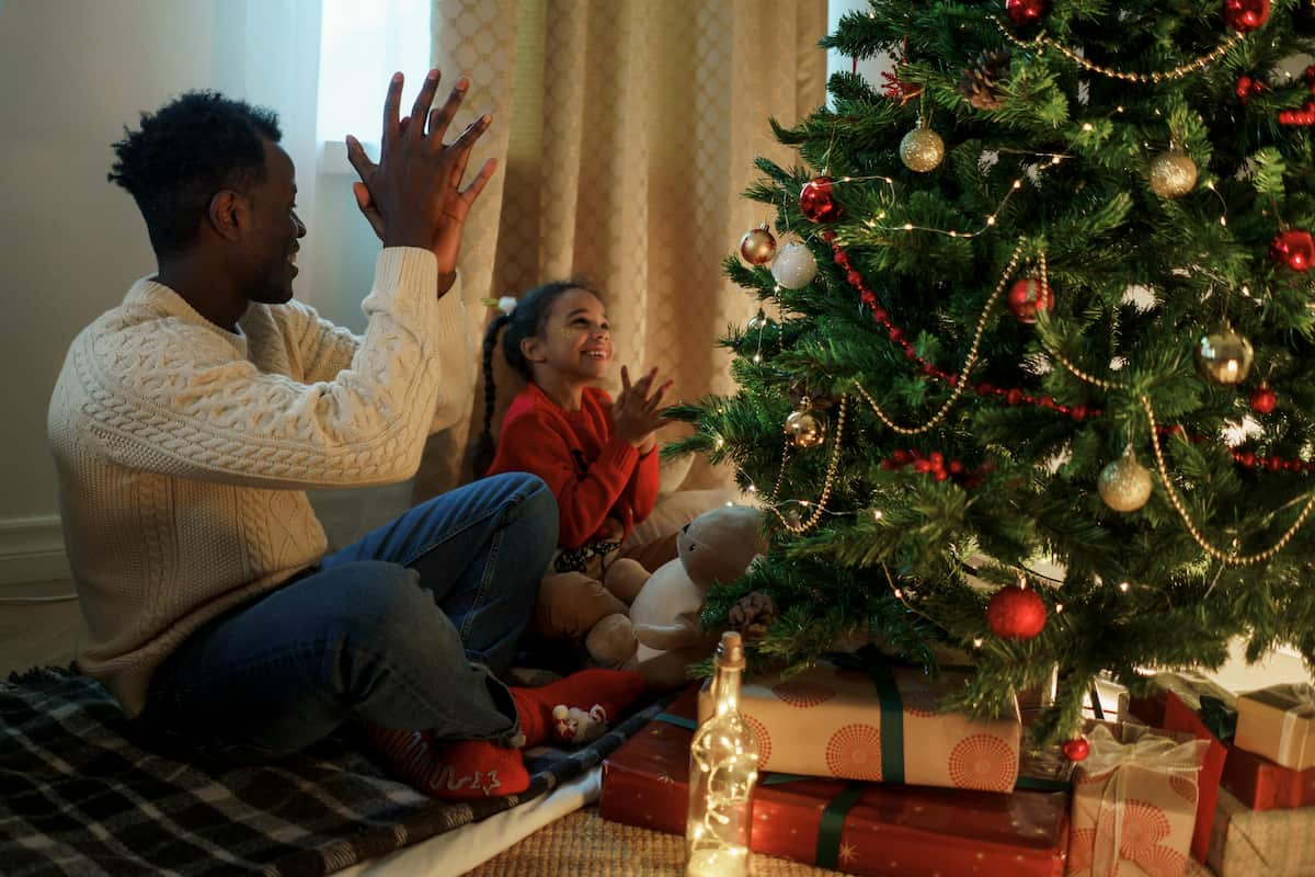 spotcovery-dad-and-daughter-sitting--near-a-christmas-tree-clapping-for-saving-for-christmas