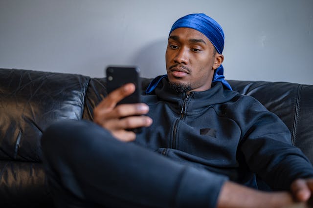 spotcovery-a-man-with-a-durag-sitting-looking-at-his-phone-tie-a-durag-fast-in-eight-simple-steps