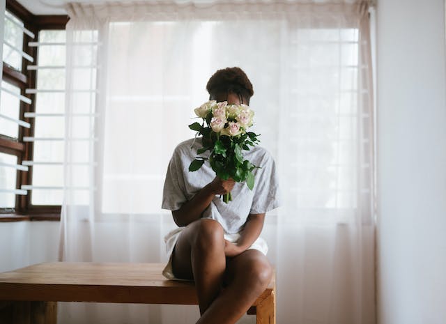 spotcovery-a-woman-sitting-on-a-table-holding-flowers-spread-love-this-month-with-six-incredible-ideas