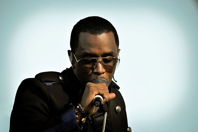 spotcovery-sean-diddy-combs-holding-a-microphone-what-is-sean-diddy-combs-charged-with-all-allegations-against-the-disgraced-rap-mogul-explained